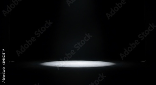 Spotlight illuminates a dark stage with a circular beam of light.