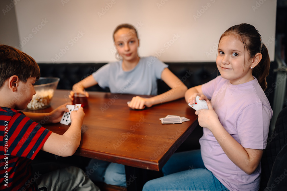 Fototapeta premium Children playing cards having family fun indoors