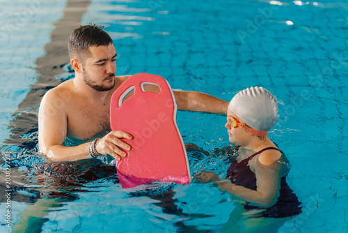 Foto Swimming instructor teaching little girl a swimming pool lesson