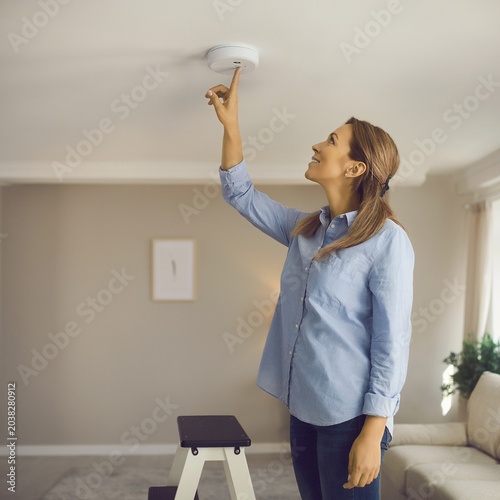 Woman Testing Home Smoke Detector in Living Room