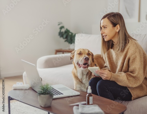 Woman with dog using laptop at home for pet care
