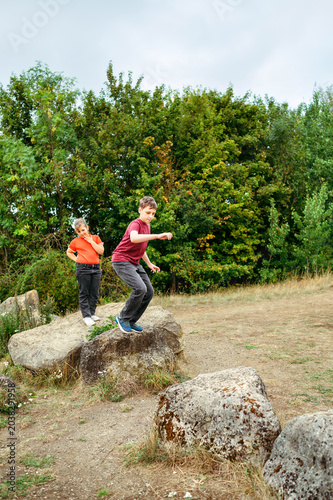 Teenager boy jumping between rocks during countryside adventure