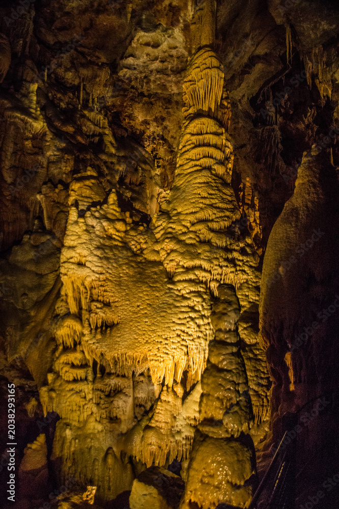 Naklejka premium Stalactites and stalagmites seen in a cave with light illuminating