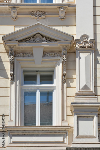 Close up of a nineteenth century architectural window with a triangular pediment and classical stucco ornaments on a historic building facade in Zagreb, Croatia.