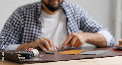 фотографія Complex and painstaking work, Male tailor crafting leather goods with sewing too