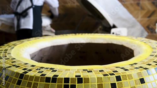 A man bakes bread cakes in a traditional Asian tandoor oven.