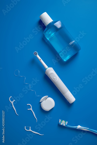 Fotografía Top view of set a electric toothbrush, dental floss and mouthwash on blue background