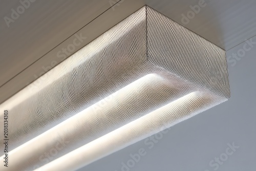 Modern interior ceiling light with a textured finish and soft, ambient illumination. The rectangular fixture emits a warm glow, creating a sophisticated and contemporary atmosphere