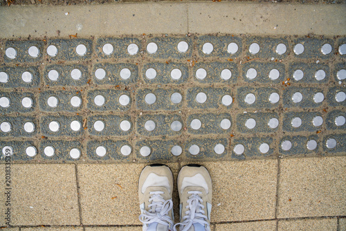 Tableau sur toile Person standing near tactile paving for visually impaired pedestrians on sidewalk