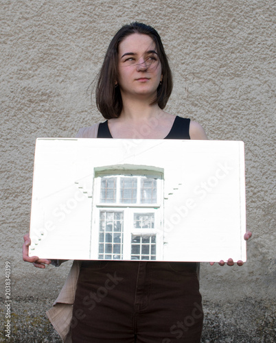 Schilderij op canvas A woman holding a mirror that reflects a window