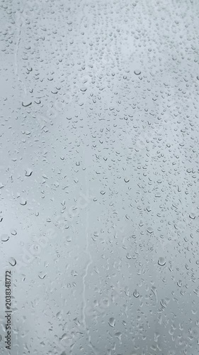 Raindrops on the window on a cloudy day. Vertical 4K footage