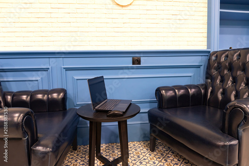 Modern cafe workspace with laptop on small table. Cozy interior and quiet freelance work atmosphere. Creative business concept. Selective focus.