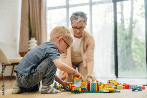 Obraz na płótnie Young boy with glasses playing with colorful building blocks on the floor while