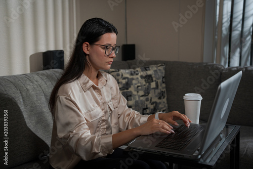 Serious woman working on laptop at home daytime showing modern remote work lifestyle and home digital productivity atmosphere