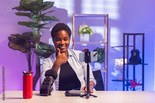 Foto Young African woman recording a video, streaming live, and giving a thumbs up ge