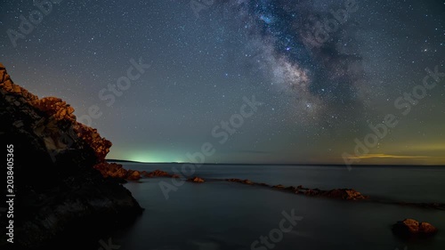 Stunning Milky Way over rocky coastline and calm sea at night