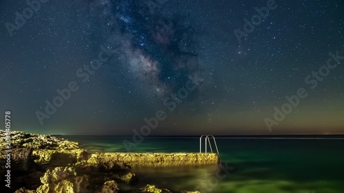 Stunning Milky Way over tranquil sea and rocky shore at night