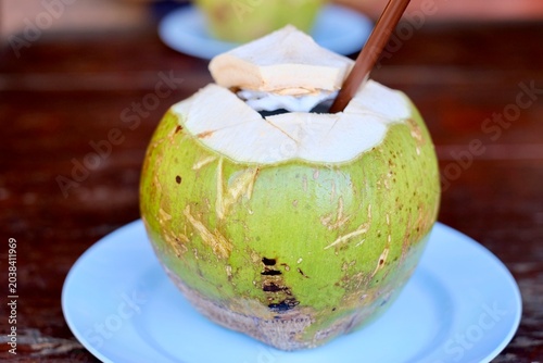 Fresh young coconuts served with straws on plastic plates at Ko Racha Seafood Restaurant - Ko Racha Yai, Thailand