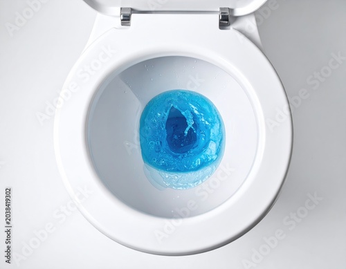 Close-up of a white toilet bowl with blue swirling liquid