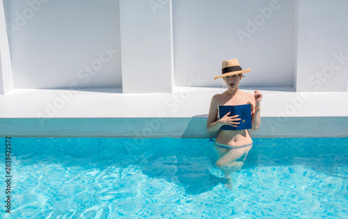 Beautiful lady in and bikini relaxing at  luxury private pool, viewed through a modern fence, summer vacation at a minimalist boutique hotel, tropical resort villa vibe