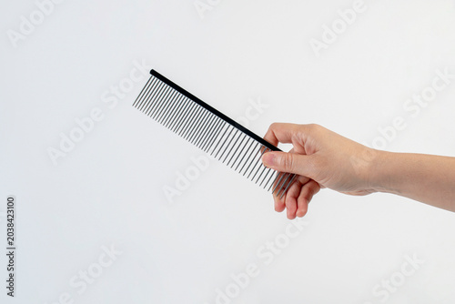 Stainless steel comb for grooming cats and dogs, and hand on white background.