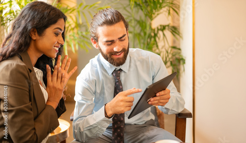 Business woman happy for her colleague who's showing his achievements on tablet computer