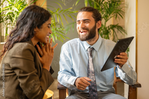 Indian man sharing his achievements with female colleague on tablet computer