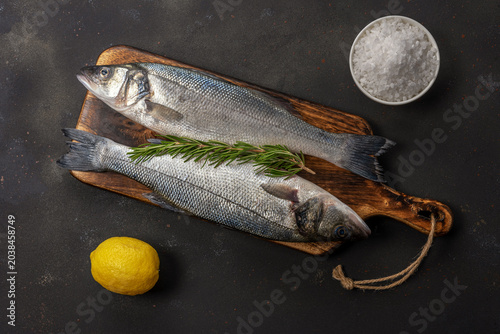 Bild auf Leinwand Fresh seabass fish with rosemary and sea salt on black table