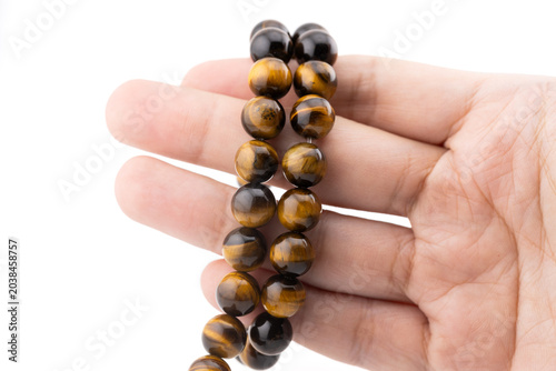 Tiger eye gemstone beads are displayed in a hand, ideal for jewelry making, bracelet making, and various DIY craft projects. These natural beads enhance creative designs.