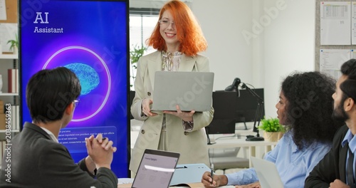 Woman software engineer or tech entrepreneur holding a laptop presenting an AI assistant application on a large display screen. Digital automation and machine learning solutions during a business.