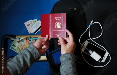 Fotografie Viajero con maleta, empacar equipaje, pasaporte, cargador teléfono móvil, dinero