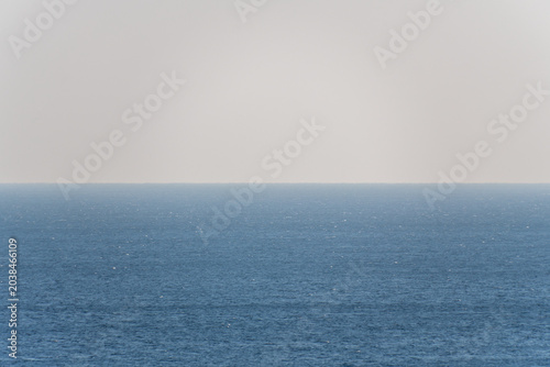Bild auf Leinwand Expansive view of calm blue ocean water under a clear sky, horizon line visible