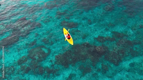 Aerial  view of a woman relaxing on a yellow kayak over a beautiful coral reef in crystal clear turquoise sea water background 	