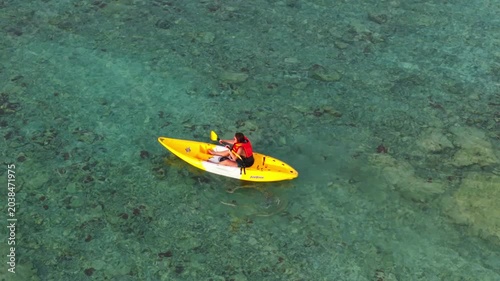 Aerial  view of a woman relaxing on a yellow kayak over a beautiful coral reef in crystal clear turquoise sea water background 	