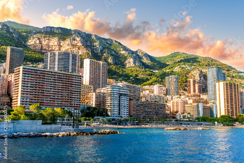 scenic cityscape of embarkment of Monte Carlo city in Monaco with blue sea water bay and amazing tall buildungs and houses along the coast. Urban mideterranean landscape with mountains and cloudy sky.