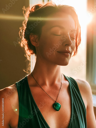 Serene woman meditating with closed eyes in warm sunlight