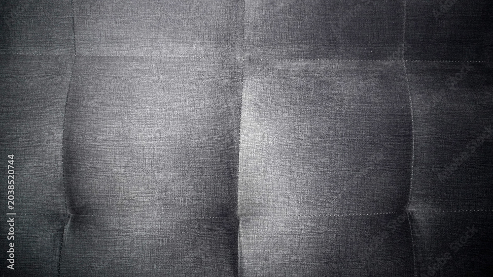 Naklejka premium Dark grey tufted fabric texture with quilted stitching pattern.