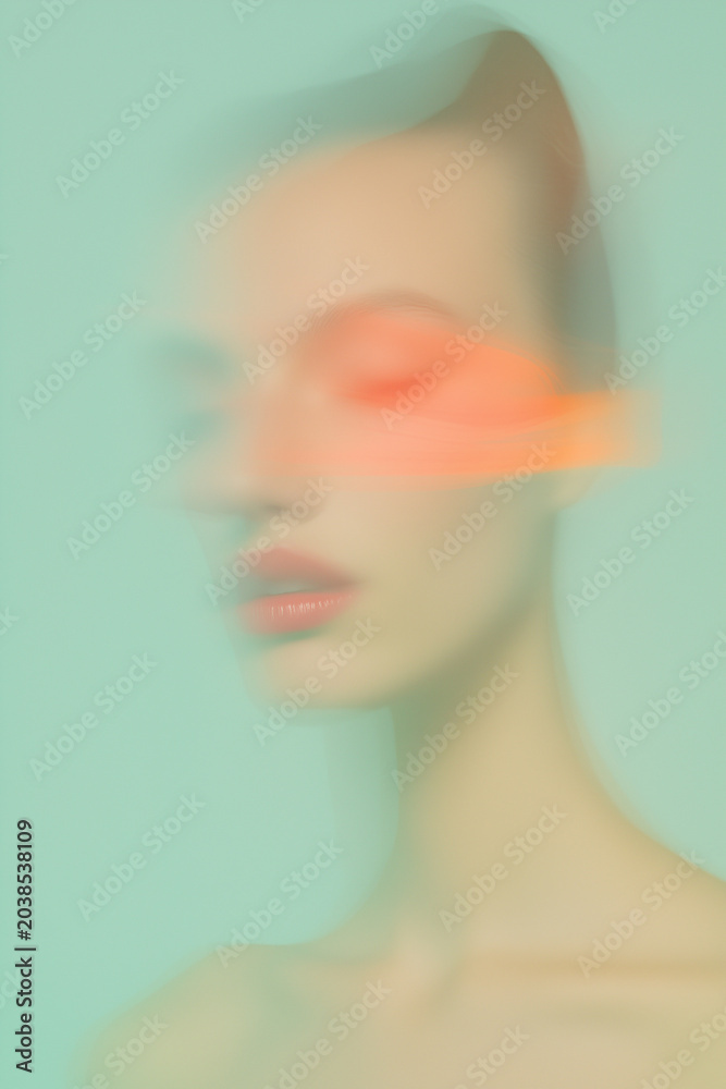 Fototapeta premium Ethereal abstract motion blur portrait of young woman with orange light streaks.