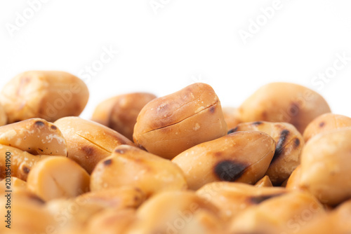 Pile of roasted hulled peanuts on white background wiht copy space for text. Close-up