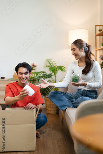 young asian couple  packing cardboard boxes to prepare to moving in a living room.