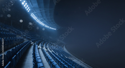 Empty stadium seats illuminated by bright stadium lights at night with a dark moody atmosphere and atmospheric dust particles floating