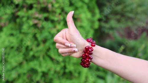 A fashionable accessory: a red garnet bracelet on a beautiful female hand with a French manicure.