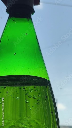 A woman opens a bottle of sparkling water and gas bubbles come out of the bottle