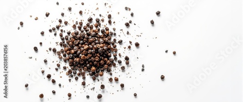 Frozen motion of black pepper seeds splashing against white backdrop