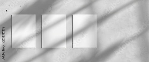 Flat lay shot of empty square flyers casting soft shadows on a textured pale grey background
