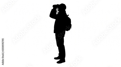 Silhouette of an adventurous man with a backpack using binoculars for distant observation and exploration