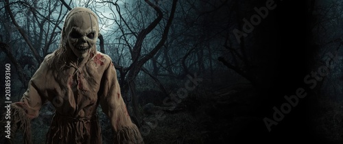Halloween horror scarecrow dressed in burlap standing among dense eerie woods with copy space