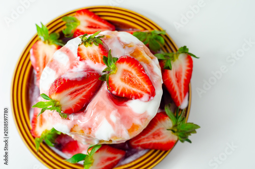 Fresh strawberries rest atop a creamy pancake stack
