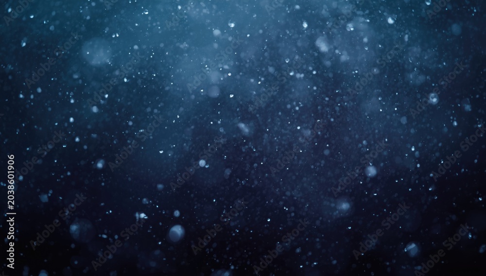 Fototapeta premium Drizzling blue snowflakes sparkling with moisture over a dark wintery backdrop