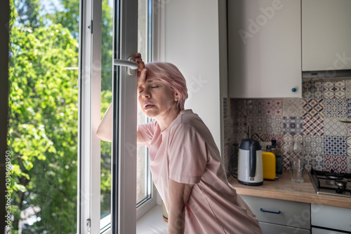 Bild auf Leinwand Tired midlife woman leaning near open window trying to cool down during overheat